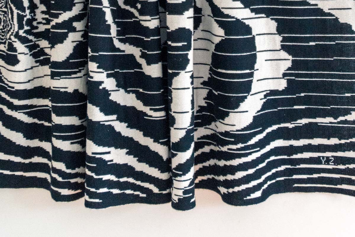 Closeup of folds at the bottom of a draped textile item, that shows a knitted black and white wood grain pattern